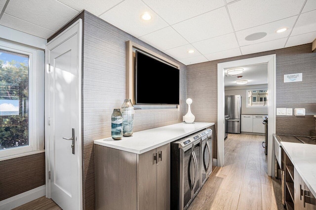 kitchen with freestanding refrigerator, light wood-style flooring, washing machine and clothes dryer, and wallpapered walls