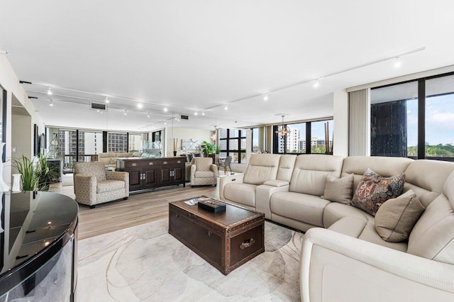 living area with floor to ceiling windows, visible vents, plenty of natural light, and light wood-style flooring