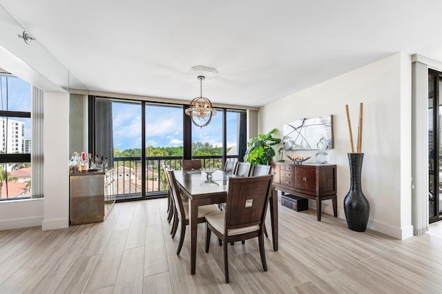 dining space featuring baseboards, a wall of windows, light wood-style flooring, and an inviting chandelier