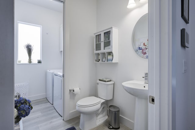 bathroom with toilet, baseboards, separate washer and dryer, and wood finished floors