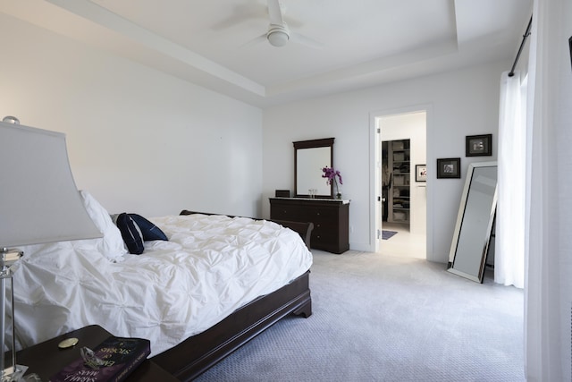 bedroom featuring a raised ceiling, a ceiling fan, and light colored carpet