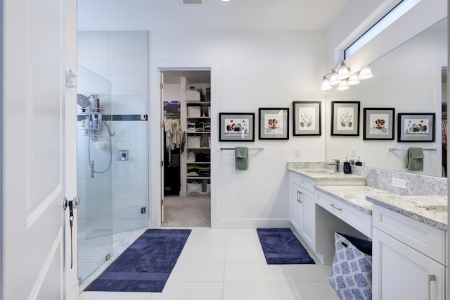 full bath with vanity, baseboards, a spacious closet, tile patterned floors, and a stall shower