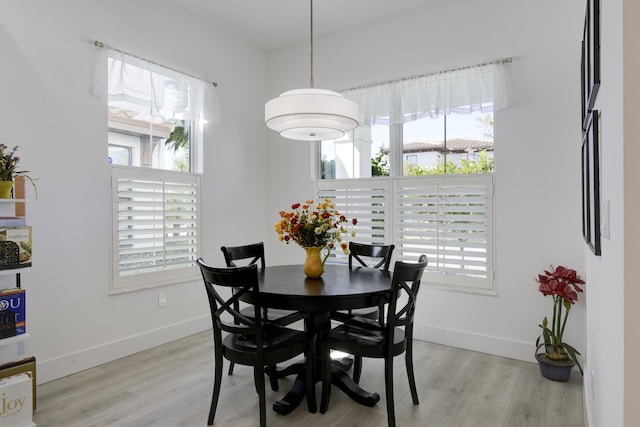 dining space featuring light wood-style floors, a wealth of natural light, and baseboards