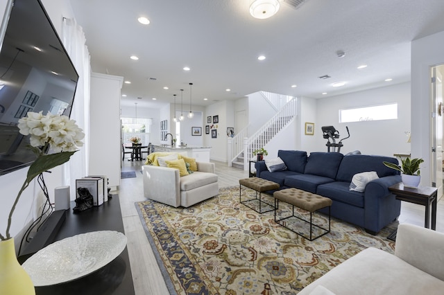 living area featuring light wood finished floors, stairway, and recessed lighting