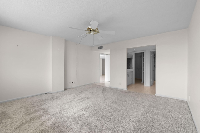 empty room with baseboards, a textured ceiling, visible vents, light carpet, and ceiling fan