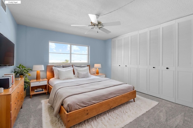 bedroom with a textured ceiling, visible vents, ceiling fan, and light carpet