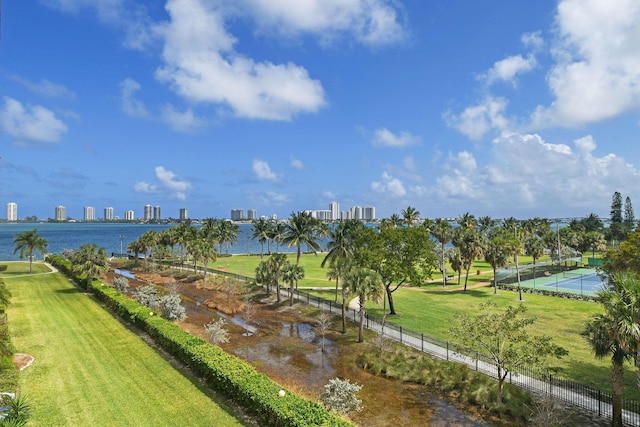 view of home's community with a view of city, a water view, fence, and a yard