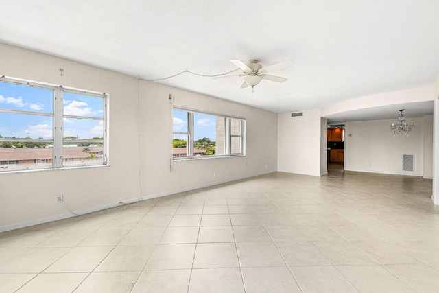 empty room featuring light tile patterned floors, ceiling fan with notable chandelier, baseboards, and visible vents