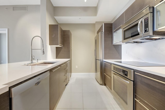 kitchen featuring modern cabinets, appliances with stainless steel finishes, light countertops, a sink, and light tile patterned flooring