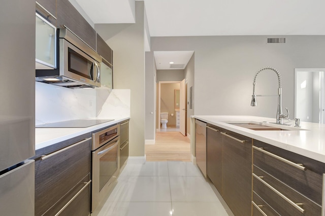 kitchen with stainless steel appliances, a sink, visible vents, light countertops, and modern cabinets