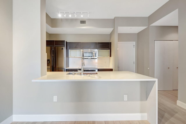 kitchen with stainless steel appliances, light countertops, visible vents, a sink, and dark brown cabinetry