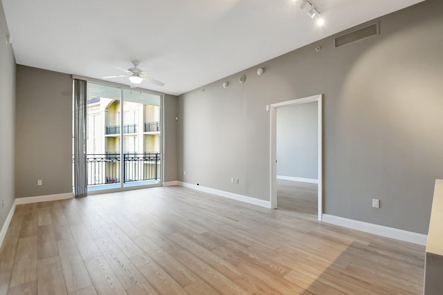 unfurnished room with ceiling fan, light wood finished floors, visible vents, and floor to ceiling windows