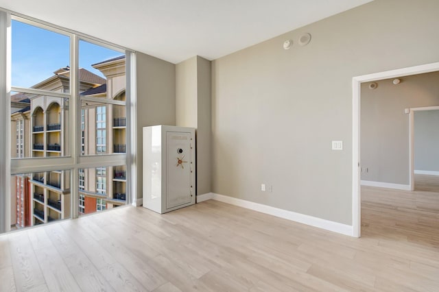 empty room with floor to ceiling windows, baseboards, and wood finished floors