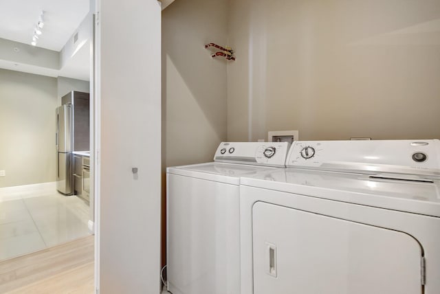 laundry area with washer and clothes dryer, light wood finished floors, rail lighting, visible vents, and laundry area