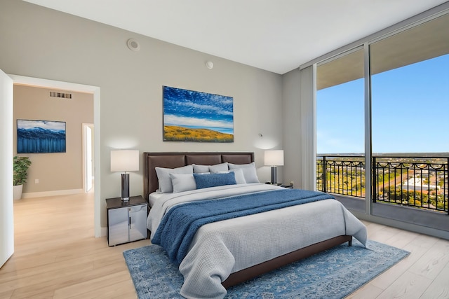 bedroom with baseboards, access to outside, light wood finished floors, and floor to ceiling windows