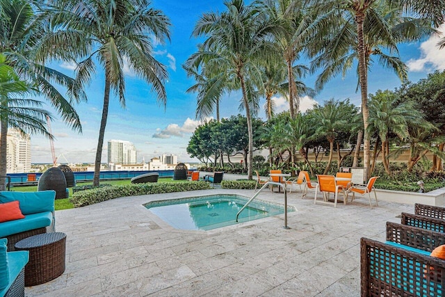 view of pool with a hot tub, a city view, and a patio