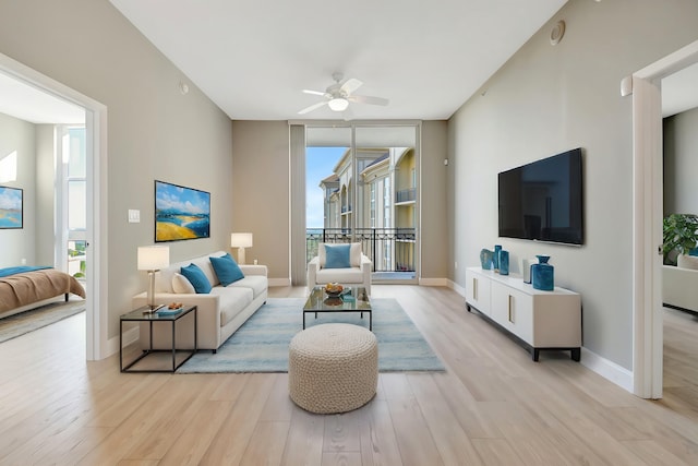 living area with a ceiling fan, expansive windows, baseboards, and light wood finished floors