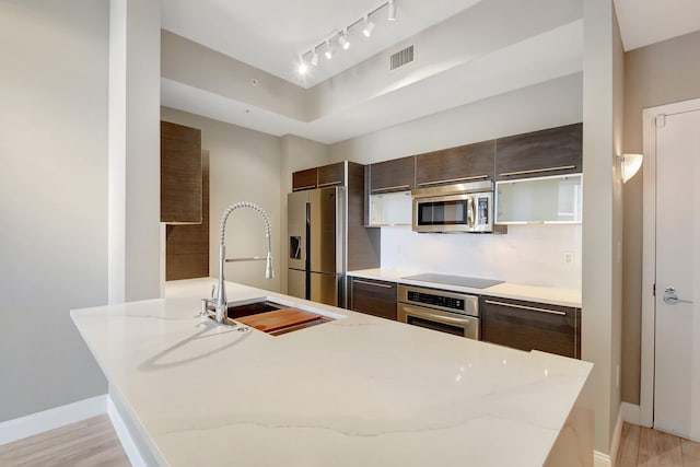 kitchen with visible vents, appliances with stainless steel finishes, dark brown cabinets, and a sink