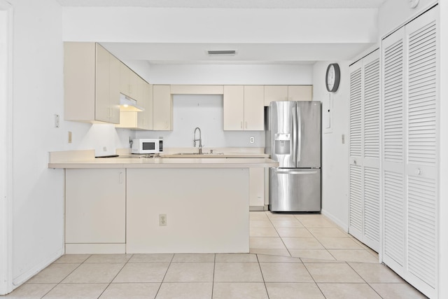 218 SE Village Dr Unit 218, Port Saint Lucie, FL 34952 - kitchen with stainless steel refrigerator with ice dispenser, white microwave, a peninsula, light countertops, and a sink