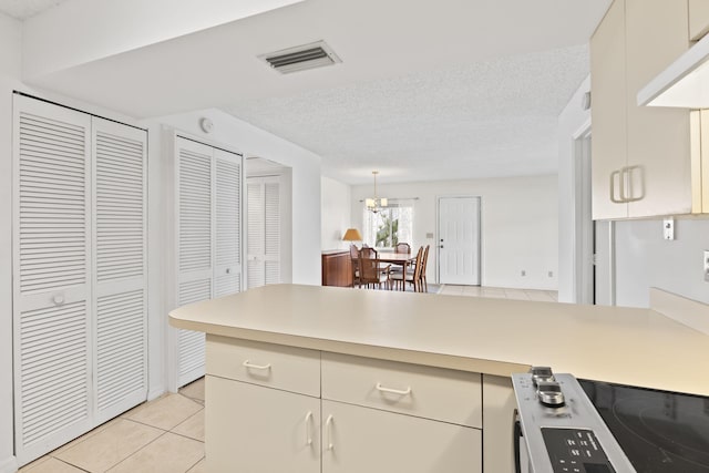 218 SE Village Dr Unit 218, Port Saint Lucie, FL 34952 - kitchen with a peninsula, light countertops, light tile patterned floors, electric range, and a chandelier
