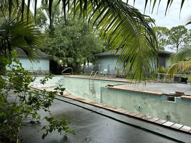 view of pool with fence and an empty pool