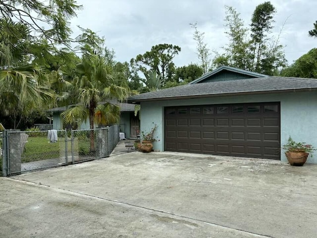 ranch-style home with a garage, a fenced front yard, a shingled roof, and stucco siding