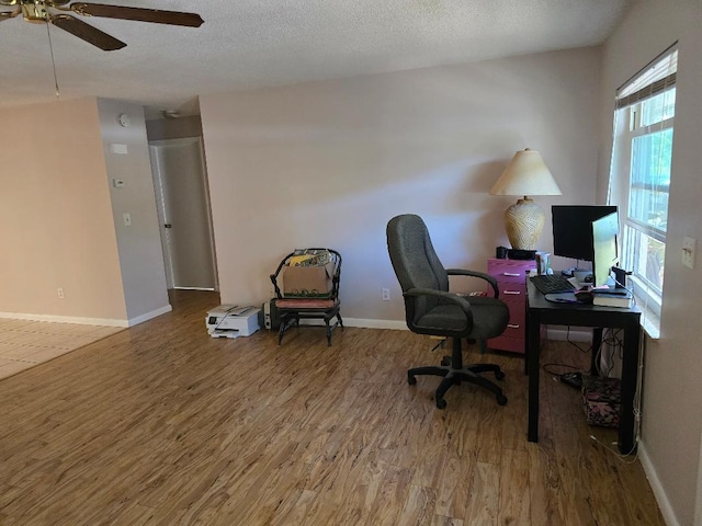 home office featuring a textured ceiling, wood finished floors, a ceiling fan, and baseboards