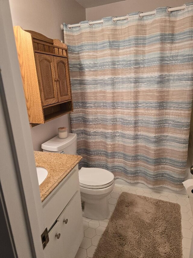 bathroom with a shower with curtain, vanity, toilet, and tile patterned floors