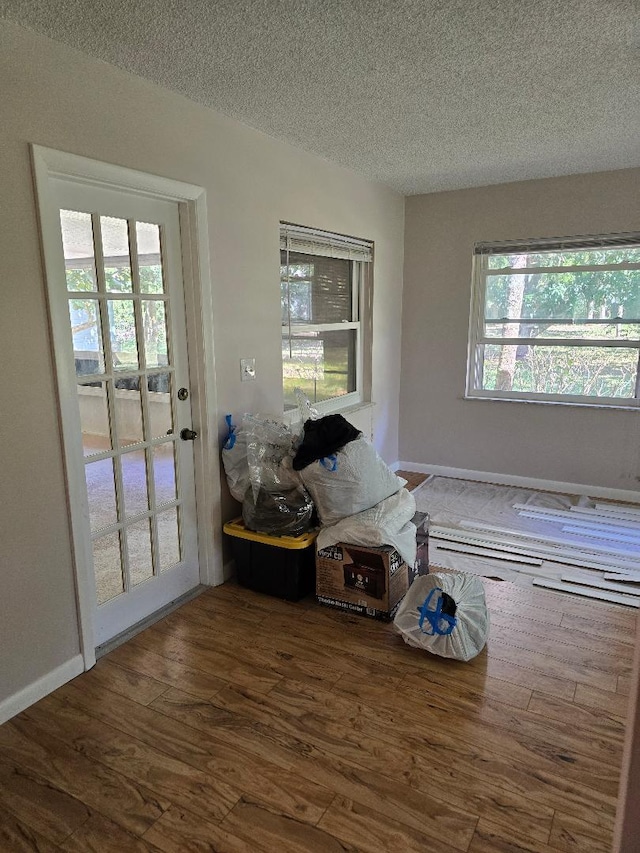 entryway with a textured ceiling, baseboards, and wood finished floors