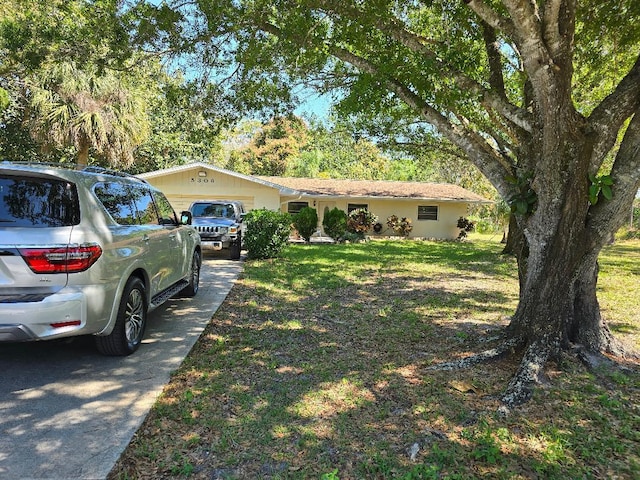 ranch-style home featuring driveway, an attached garage, and a front yard