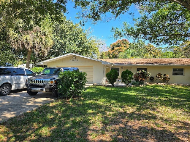 single story home featuring a front yard, concrete driveway, and an attached garage