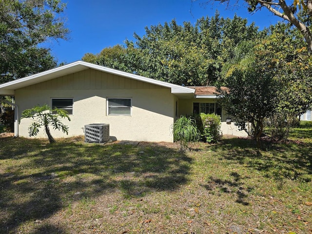 view of property exterior featuring stucco siding, a yard, and central air condition unit