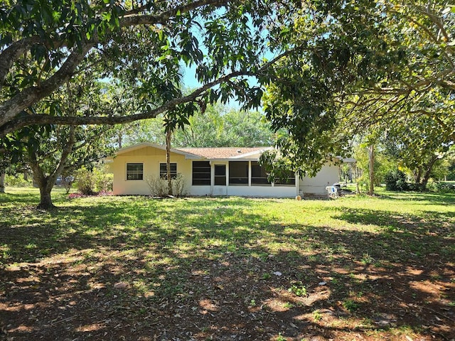 back of property featuring a sunroom and a lawn