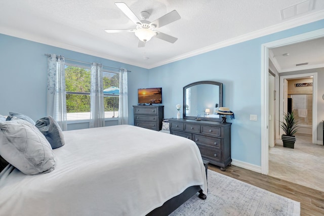 bedroom with visible vents, light wood-style flooring, a textured ceiling, and ornamental molding