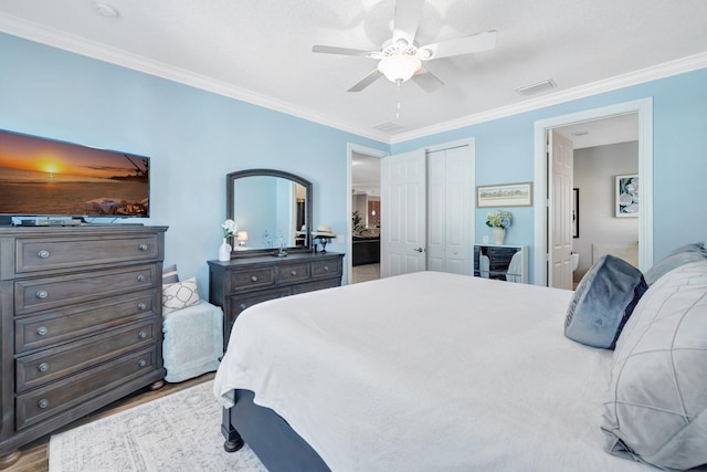 bedroom with a ceiling fan, wood finished floors, visible vents, ornamental molding, and a closet