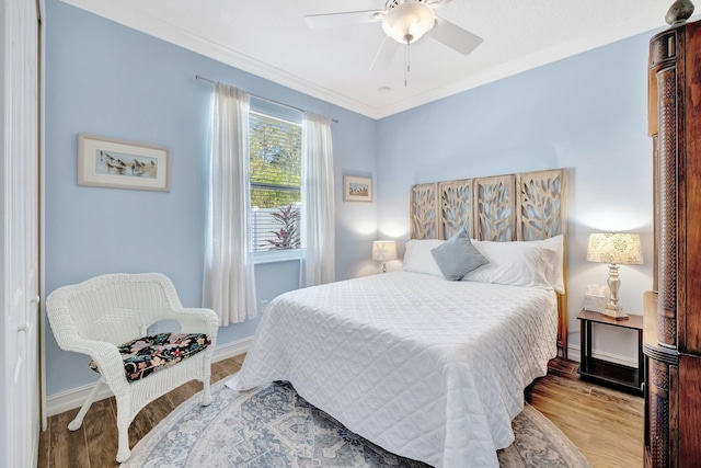 bedroom featuring ceiling fan, baseboards, wood finished floors, and ornamental molding