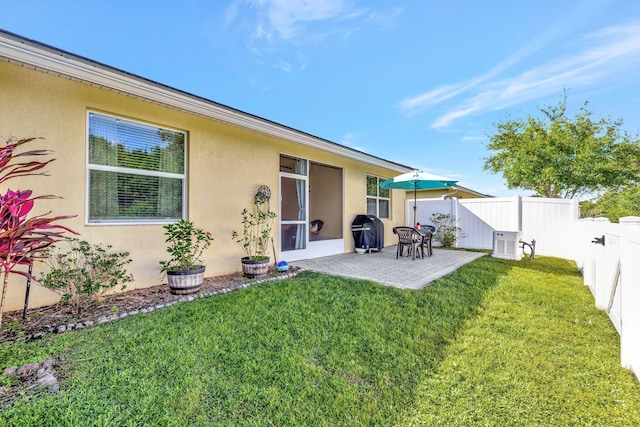 rear view of house featuring a patio area, stucco siding, a lawn, and a fenced backyard