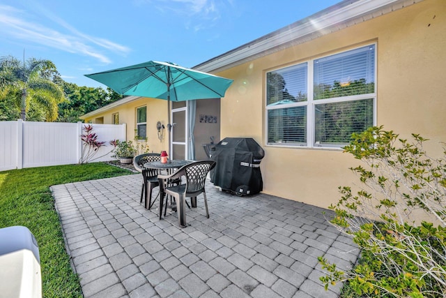 view of patio featuring grilling area, outdoor dining area, and fence