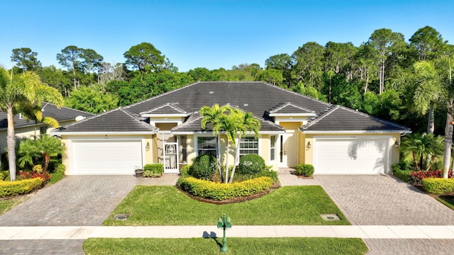 single story home featuring decorative driveway, an attached garage, and stucco siding