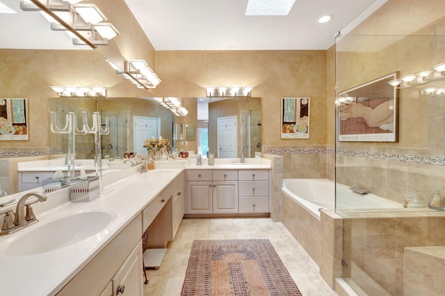 full bath featuring a skylight, tiled bath, tiled shower, tile patterned floors, and vanity