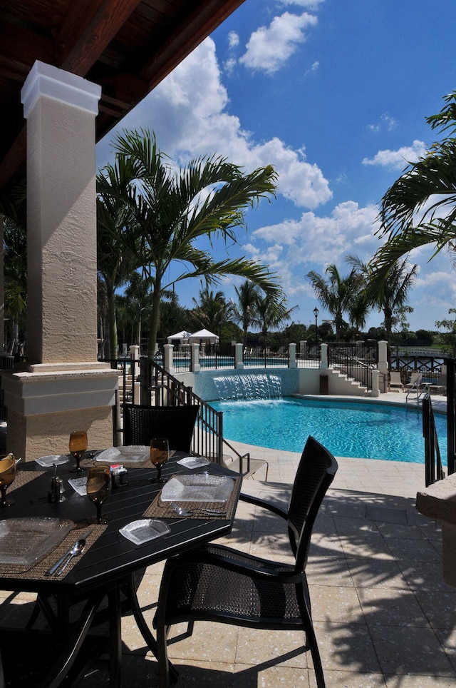 community pool with outdoor dining space, fence, and a patio