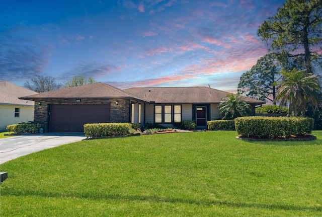 view of front of house with an attached garage, a yard, stone siding, and driveway