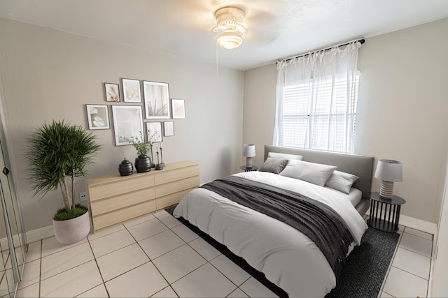 bedroom featuring light tile patterned floors, baseboards, and a ceiling fan