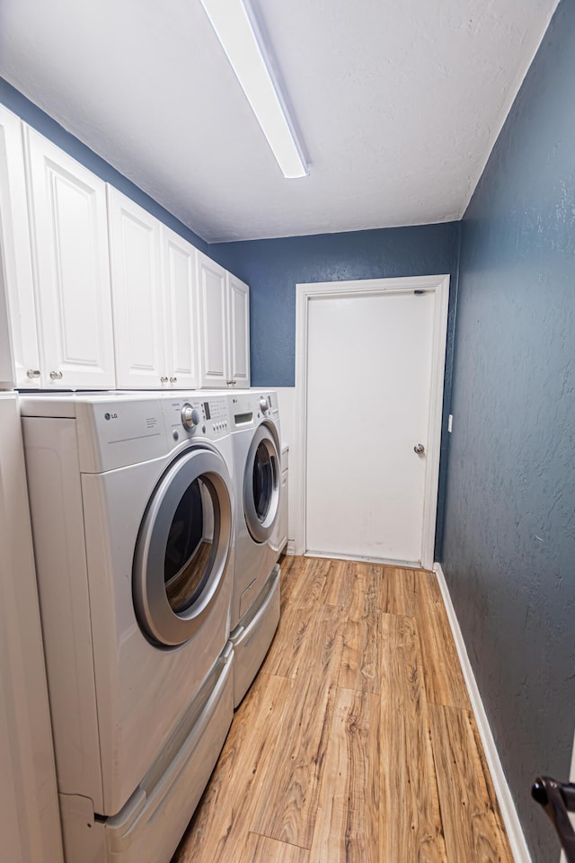 washroom with cabinet space, light wood-type flooring, a textured wall, and separate washer and dryer