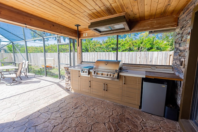 view of patio / terrace with exterior kitchen, area for grilling, a lanai, and fence