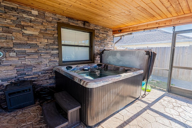 view of patio featuring fence, a lanai, and a hot tub