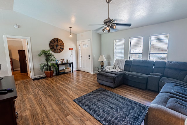 living room with a textured ceiling, dark wood finished floors, baseboards, ceiling fan, and vaulted ceiling