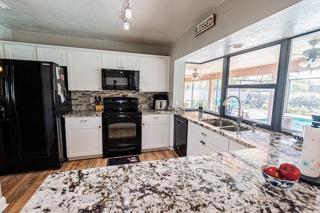 kitchen featuring black appliances, white cabinets, light wood finished floors, and a sink