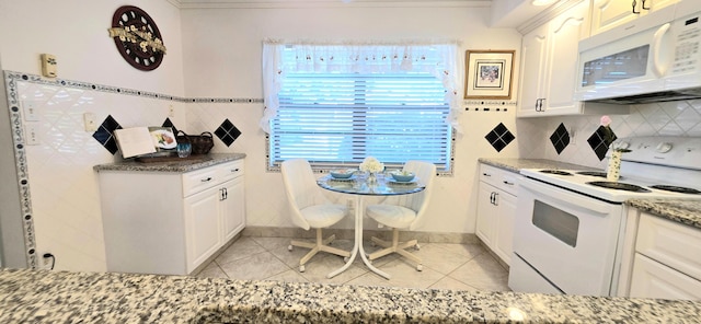 kitchen with stone countertops, white appliances, white cabinets, and light tile patterned floors