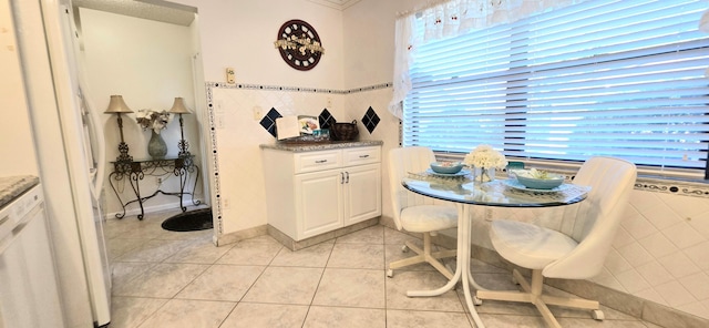 dining room featuring light tile patterned floors, a wealth of natural light, and tile walls